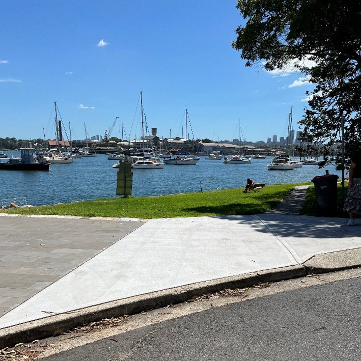 Path and small grassy area in front of a harbour with recreational boats
